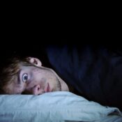 A man laying in bed with his head on the pillow.