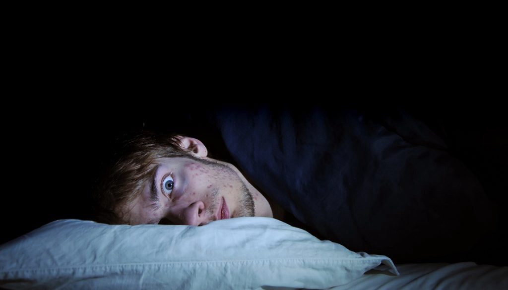 A man laying in bed with his head on the pillow.