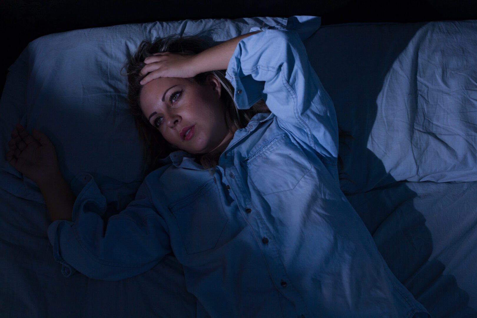 A woman laying in bed with her head on the pillow.