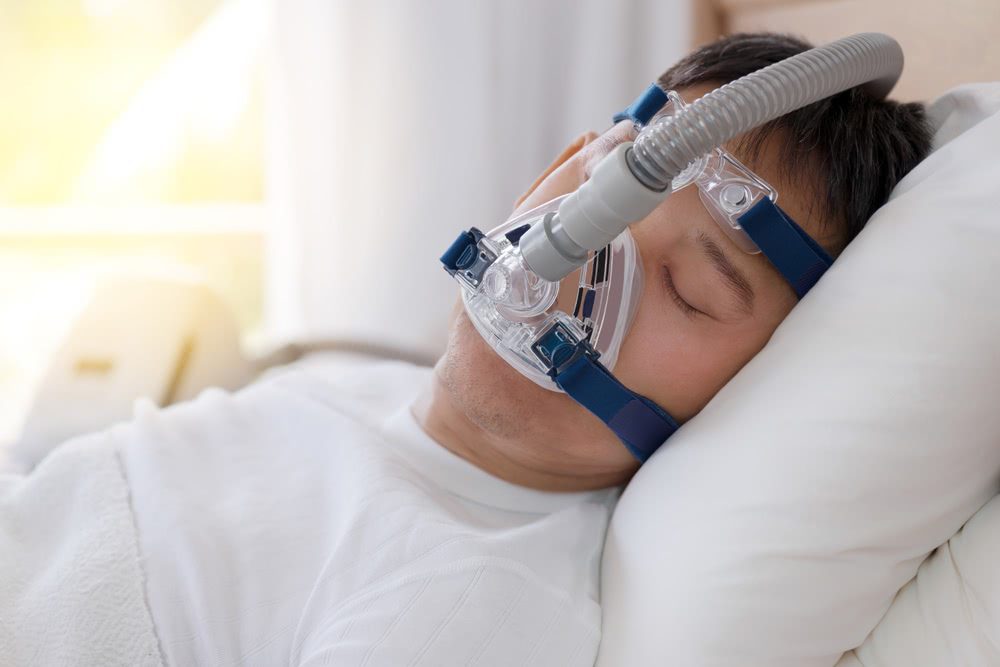 A man with an oxygen mask on is sleeping.