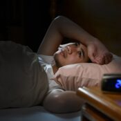 A person laying in bed with their head on the pillow.