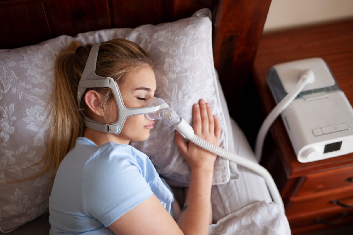 A woman laying in bed with an oxygen mask on.