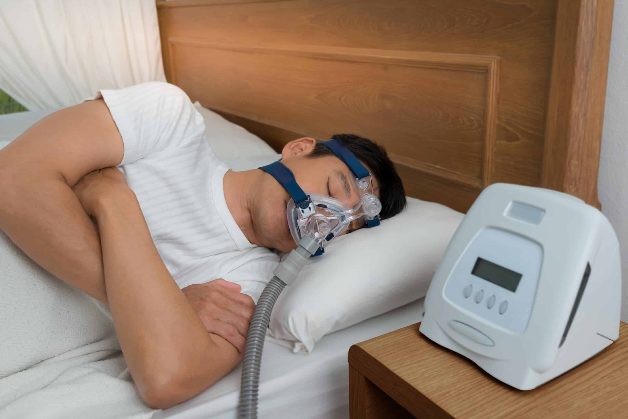 A man sleeping in bed with an oxygen mask on.