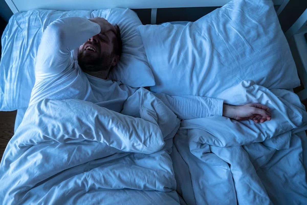 A man laying in bed with his head on the pillow.