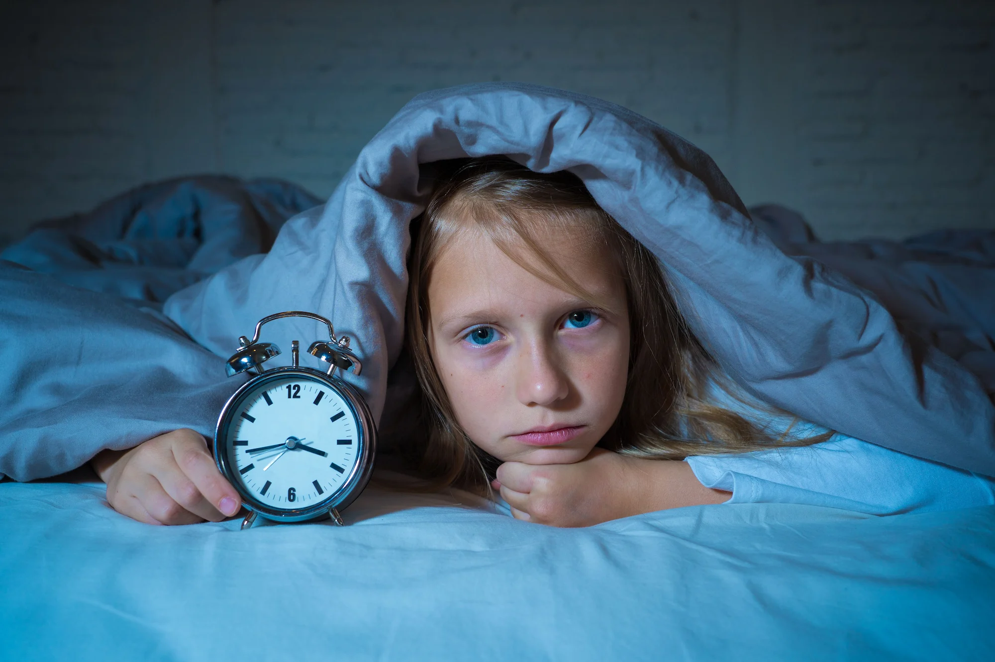 A girl is holding an alarm clock in her hand.