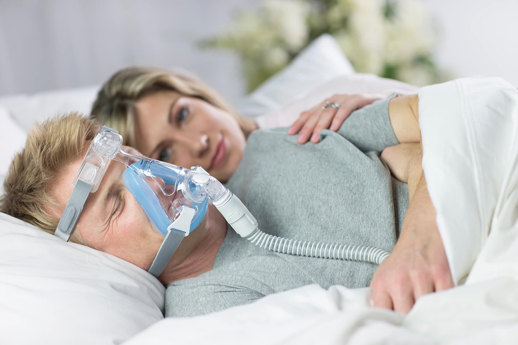 Man sleeping with CPAP mask in bed.